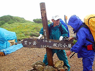 弓折岳頂上で(折れた標識を持つ鮫田さん)
